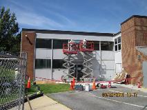 Two BARCO Enterprises Inc. employees conduct lead abatement activity on the exterior of Building 17. The workers were wearing appropriate coveralls, respirators, safety glasses, hard hats and fall protection gear as they worked on scissor lifts.