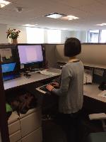 An employee uses the proper ergonomic sit/stand workstation.