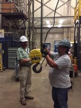 Two Goddard Space Flight Center Lifting Devices and Equipment technicians perform a monthly safety inspection of a crane at Goddard-Greenbelt. They have barricaded the area and are wearing the appropriate Personal Protective Equipment for the job.